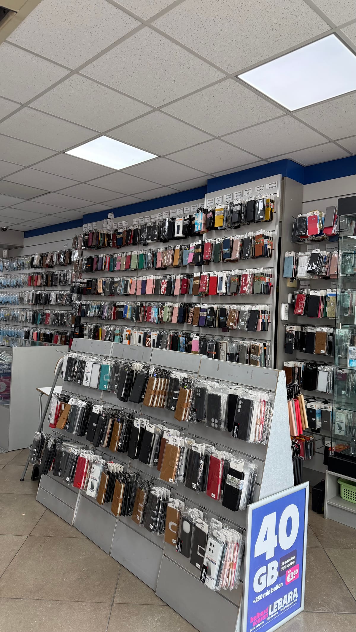 Wand vol telefoonhoesjes en een displayzuil in de winkel van Hosseini Telecom aan de Hofstraat in Apeldoorn
